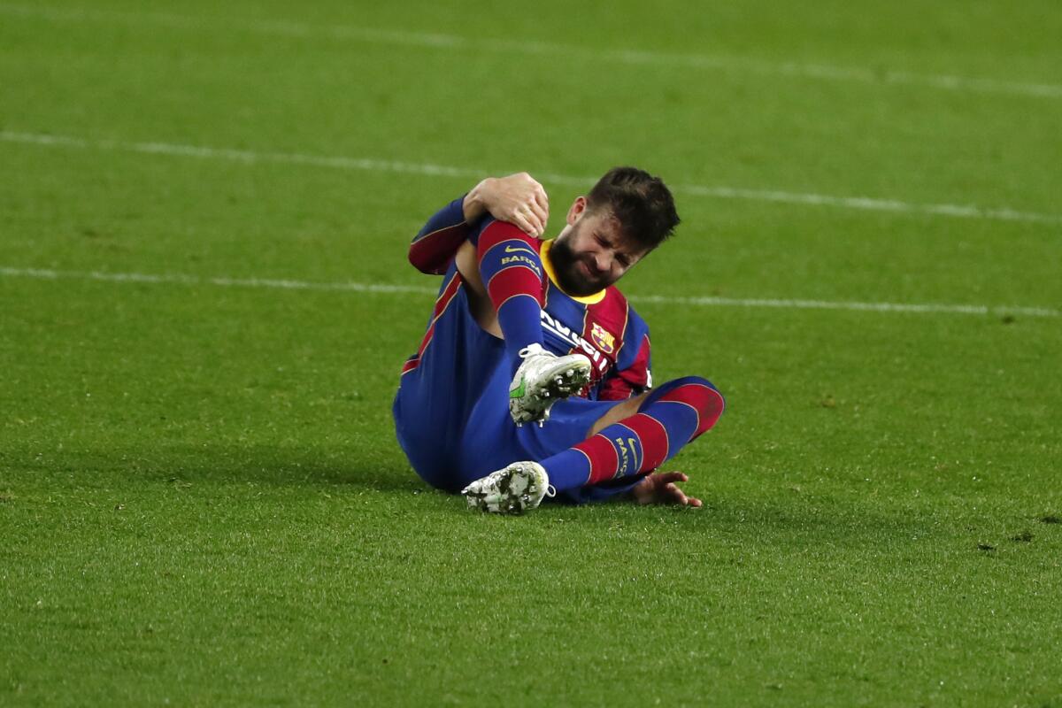 Barcelona's Gerard Pique holds his knee after getting injured during the the Copa del Rey semifinal, second leg, soccer match between FC Barcelona and Sevilla FC at the Camp Nou stadium in Barcelona, Spain, Wednesday March 3, 2021. (AP Photo/Joan Monfort)
