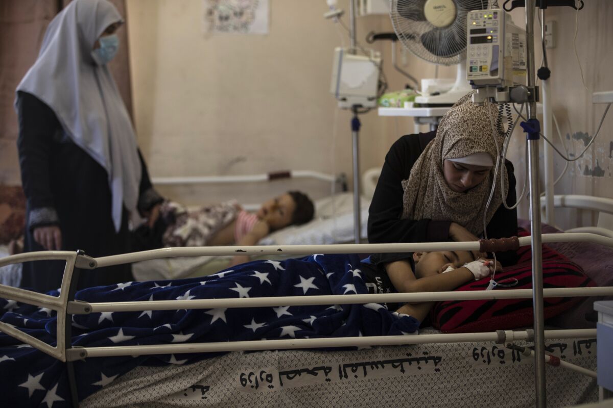 The mother of Yazan Al-zaharna, 9, comforts him as he rests at the Shifa hospital in Gaza City, Thursday, May 13, 2021, where he is receiving treatment for wounds caused by a May 10 Israeli strike that hit a nearby his family house in town of Jabaliya. Just weeks ago, the Gaza Strip’s feeble health care system was struggling with a runaway surge of coronavirus cases. Now doctors across the crowded coastal enclave are trying to keep up with a very different crisis: blast and shrapnel wounds, cuts and amputations. (AP Photo/Khalil Hamra)