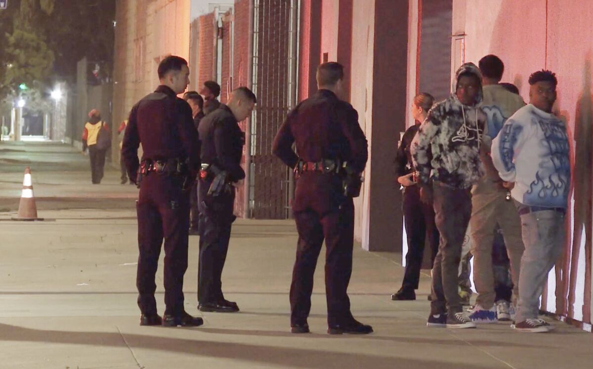 LAPD officers detain people after a shooting that left one dead and five others injured.