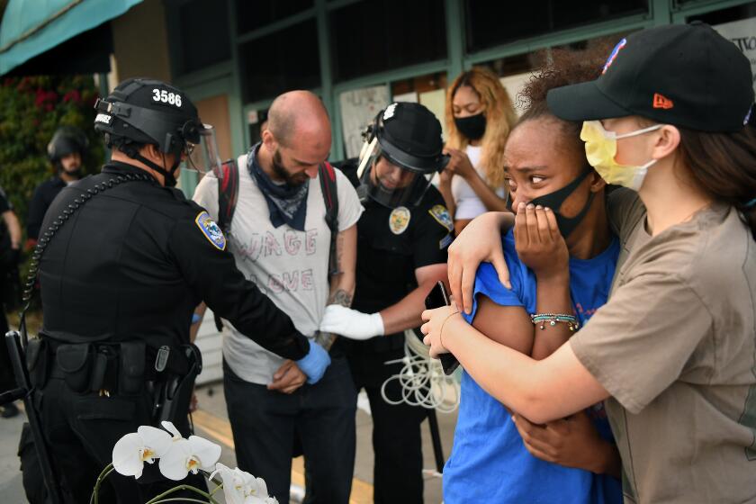 SANTA MONICA, CALIFORNIA MAY 31, 2020-Protestors embrace as another is led away in handcuffs on 5th St. in Santa Maonica Sunday. (Wally Skalij/Los Angeles Times)