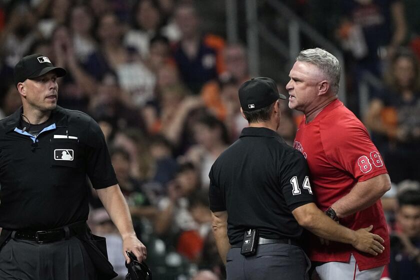 Second base umpire Mark Wegner steps in-between home plate umpire Stu Scheurwater and Angels manager Phil Nevin.