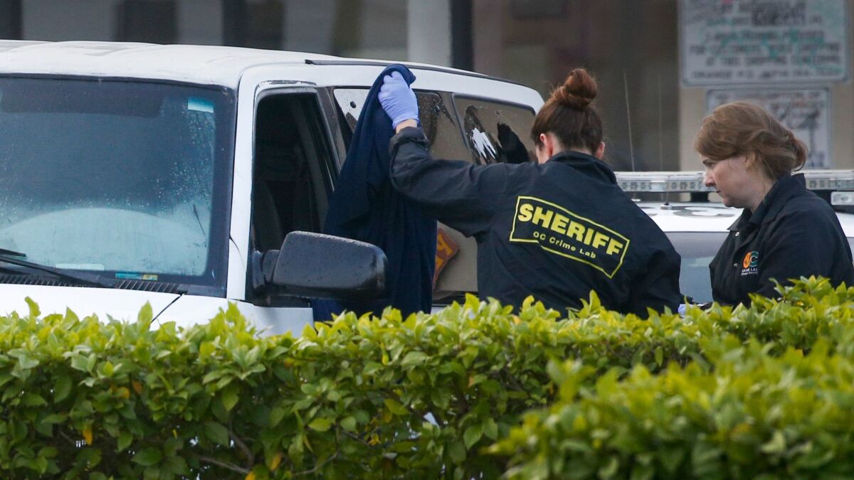 Members of the Orange County Crime Lab remove clothing from a van after a suspect was fatally shot by Orange police officers Sunday night.
