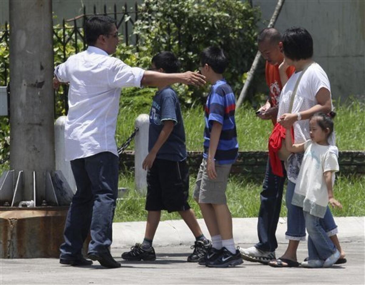 Hostage negotiators, left and fourth from left, talk to foreign tourists taken hostage by former Senior Inspector Rolando Mendoza after securing their release at Manila's Rizal Park Monday, Aug. 23, 2010, in the Philippines. Mendoza, a dismissed policeman armed with an automatic rifle seized the bus in Manila Monday with 25 people aboard, most of them Hong Kong tourists, in a bid to demand reinstatement, police said. (AP Photo/Bullit Marquez)