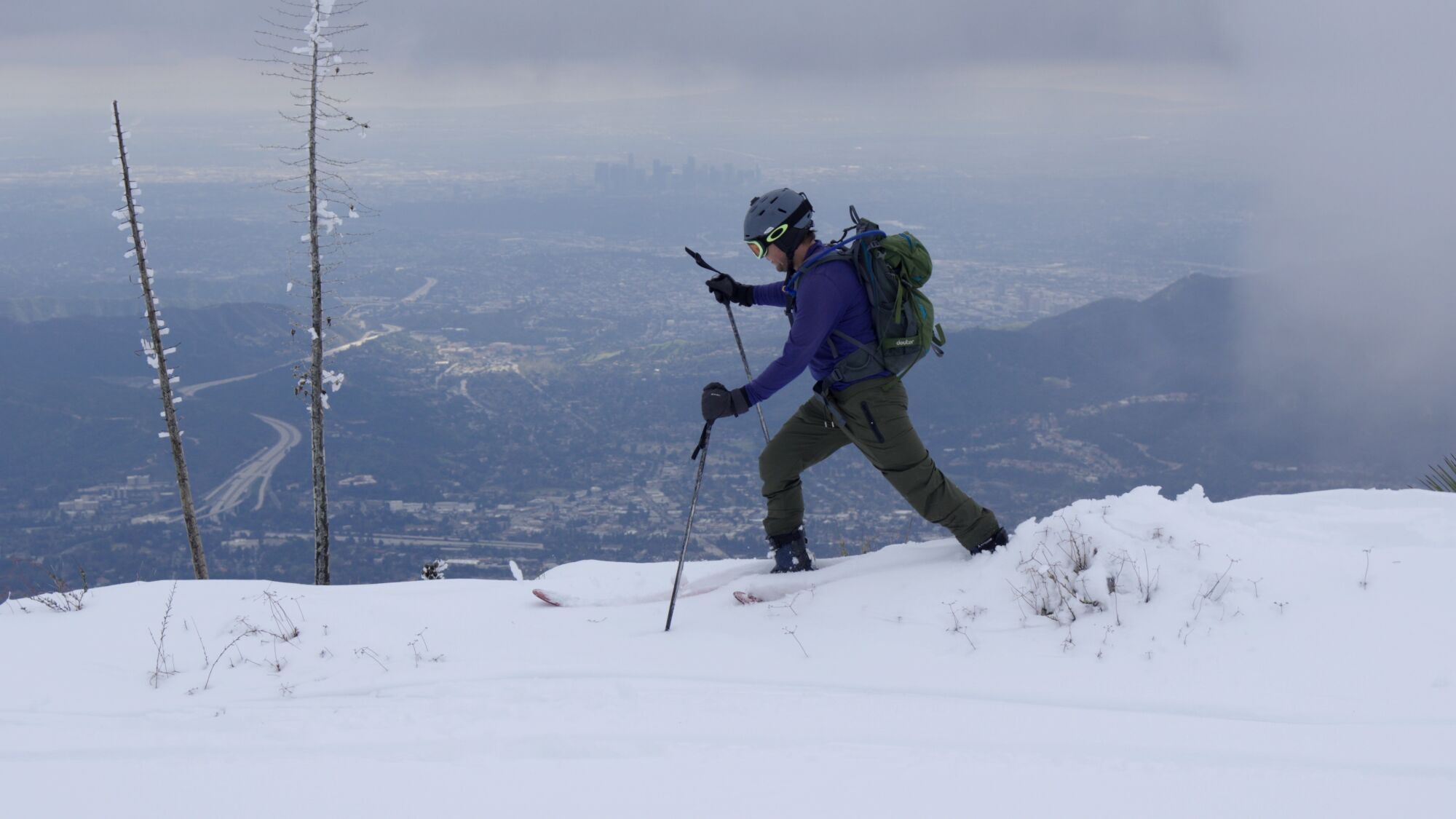 Matt Dixon skie au sommet du mont Lukens avec la ligne d'horizon du centre-ville de Los Angeles au loin.