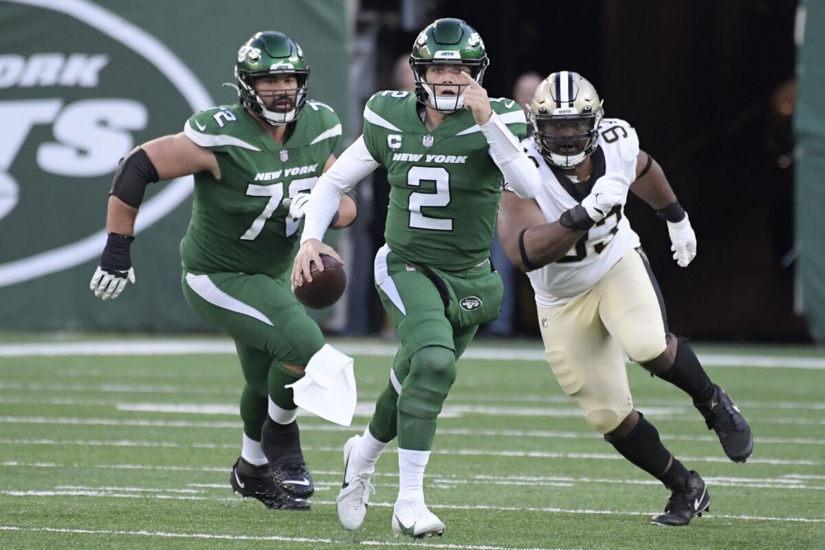 New York Jets quarterback Zach Wilson, center, tries to avoid being tackled during the second half of an NFL football game against the New Orleans Saints, Sunday, Dec. 12, 2021, in East Rutherford, N.J. (AP Photo/Bill Kostroun)