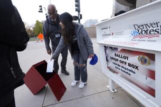 A young voter places a ballot directly into a collection box as officials prepare to load ballots from a drop box outside the Denver Elections Division headquarters early Tuesday, Nov. 8, 2022, in downtown Denver. (AP Photo/David Zalubowski)