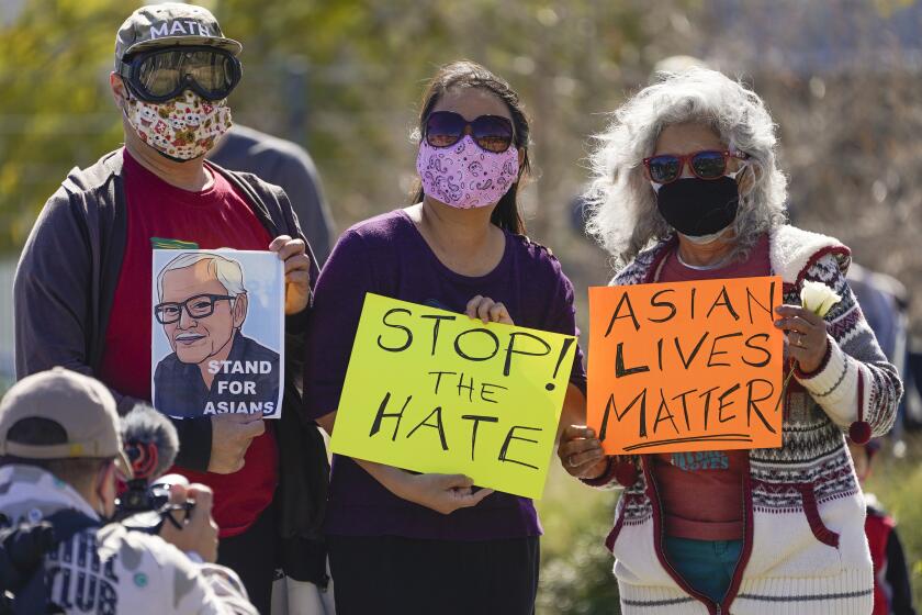 A man holds a portrait of late Vichar Ratanapakdee, left, a 84-year-old immigrant from Thailand, who was violently shoved to the ground in a deadly attack in San Francisco, during a community rally to raise awareness of anti-Asian violence and racist attitudes, in response to the string of violent racist attacks against Asians during the pandemic, held at Los Angeles Historic Park near the Chinatown district in Los Angeles, Saturday, Feb. 20, 2021. (AP Photo/Damian Dovarganes)