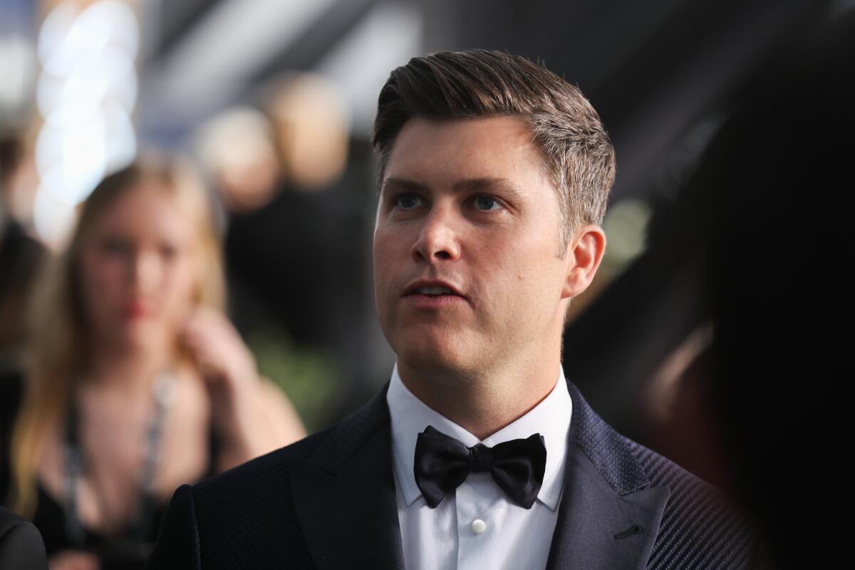 Colin Jost in a tuxedo, tilting his chin up as he speaks