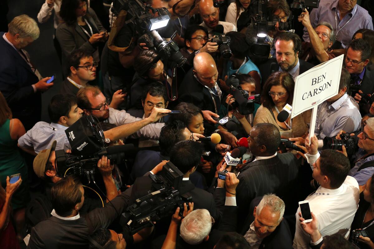 Members of the media swarm Ben Carson, lower right, in the spin room after the debate at the Reagan Library.