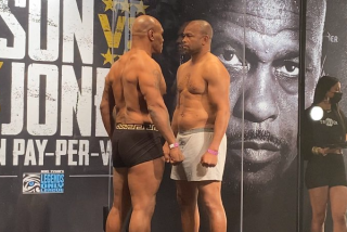 Mike Tyson, left, and Roy Jones Jr. have a stare down while separated by plexiglass after their weigh-in on Friday.
