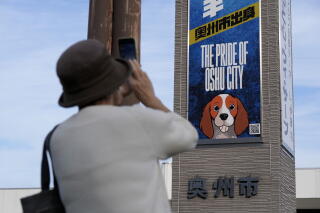 A person photographs a Dodger blue poster reading "The pride of Oshu City."
