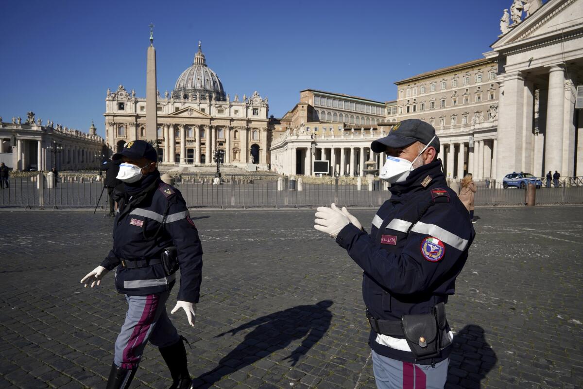 Police officers wearing masks patrol an empty St. Peter's Square at the Vatican, Wednesday, March 11, 2020. 