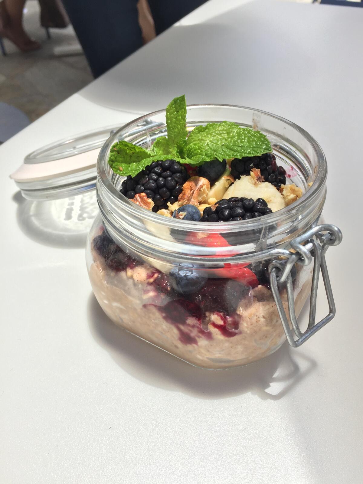A jar of chilled overnight oats and chia seeds with fresh fruit and house granola at Parakeet Cafe in La Jolla, Del Mar and Little Italy.