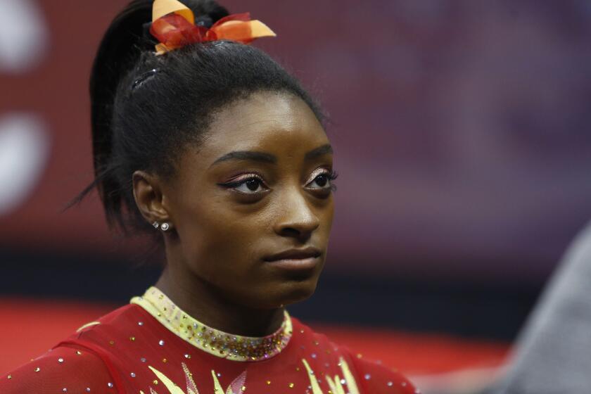 FILE - In this July 28, 2018, file photo, Olympic champion Simone Biles talks with her coach before the start of the U.S. Classic gymnastics competition in Columbus, Ohio. Biles says she’s struggling with the arrest of her brother who was charged in a shooting that left three dead. She said in a tweet Monday, Sept. 2, 2019, that her heart aches for everyone involved, especially the victims and their families. (AP Photo/Jay LaPrete, File)