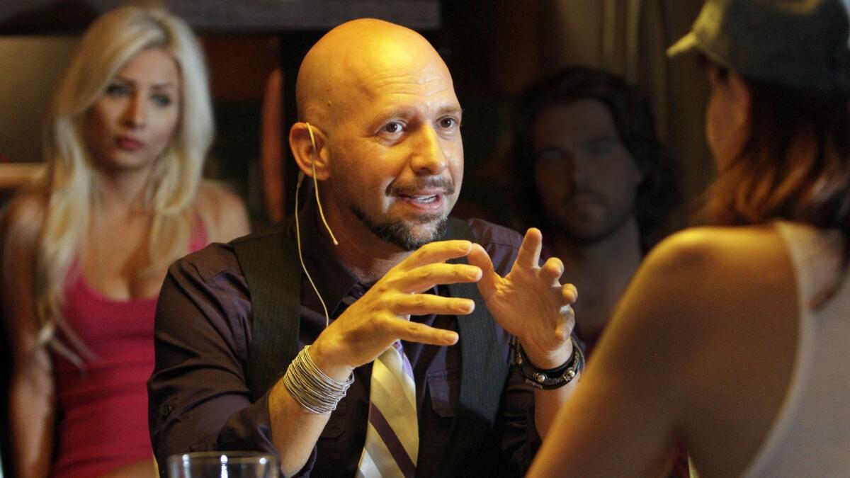 Neil Strauss and his girlfriend De La O behind him during the taping of a radio show at his home in Malibu in 2012.