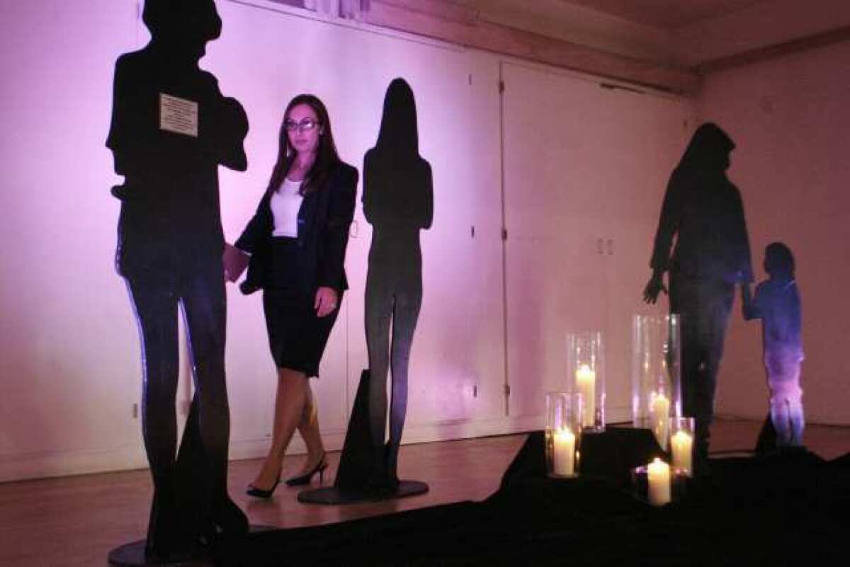 Christine Powers rearranges the silhouette figures before a candlelight vigil for victims of domestic violence, which took place at YWCA in Glendale.