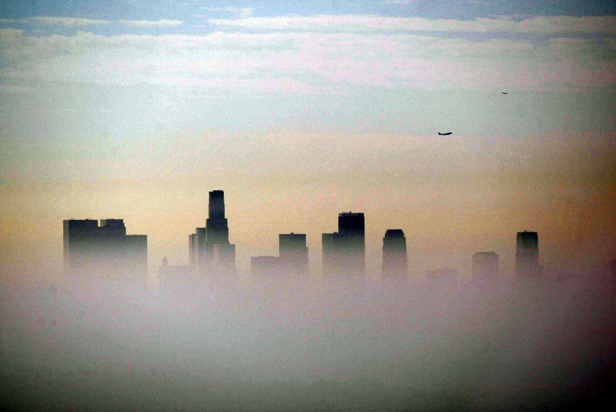A haze of smog partially obscures an urban skyline.