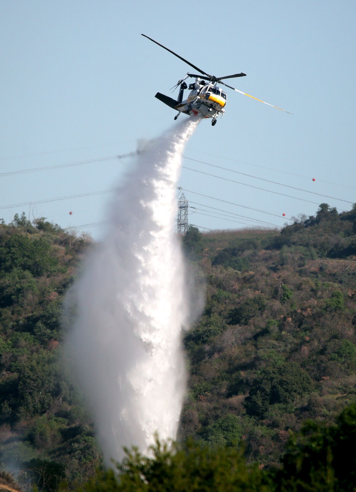 A helicopter drops water on brush.