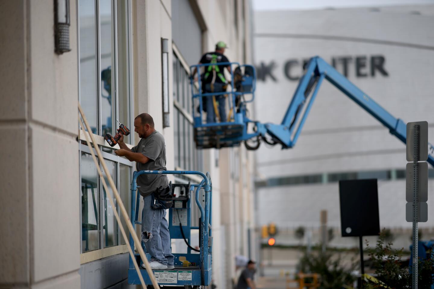 Workers attach plywood to a store front near the BOK Center in Tulsa in advance of a Trump campaign rally.