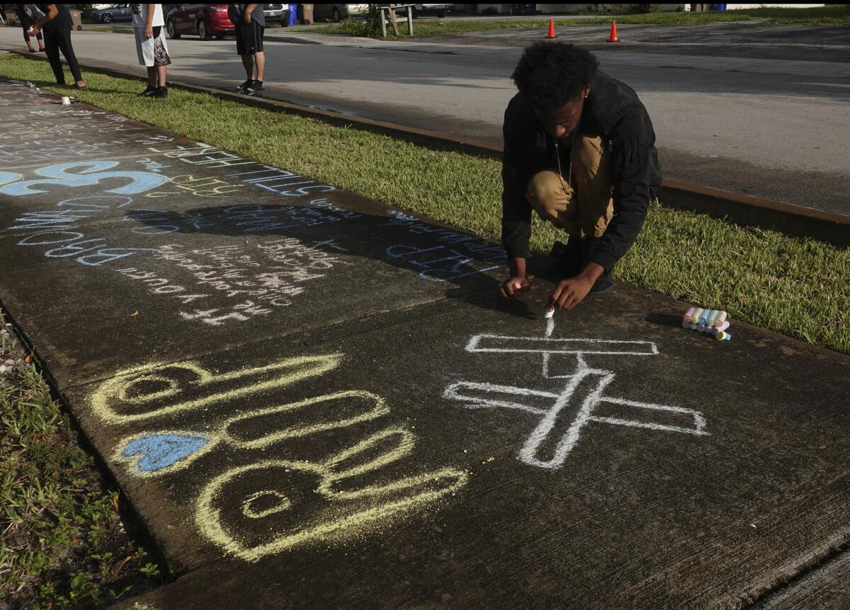 Lenar Nesmith of Pompano Beach, Fla., a fan of XXXTentacion, writes a message on the sidewalk Tuesday outside Riva Motorsports in Deerfield Beach, where the troubled rapper-singer was killed the day before.