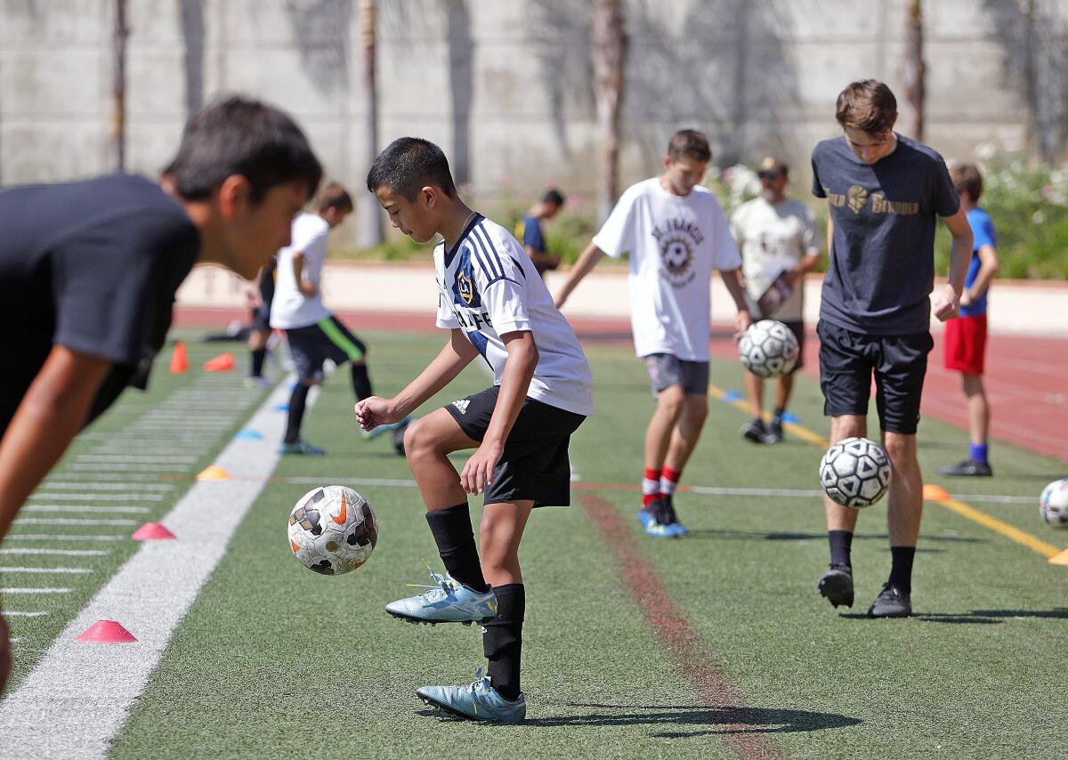 Camper Josh Ngo, 12, of Glendale, with a group, juggles the ball for a minute in a contest/drill at the St. Francis Summer Soccer Camp led by St. Francis Coach Glen Appels at St. Francis High School on Monday, July 29, 2019. The camp encourages boys and girls from six to eighteen to learn soccer skills in shooting, dribbling, passing, and ball control through drills and video.