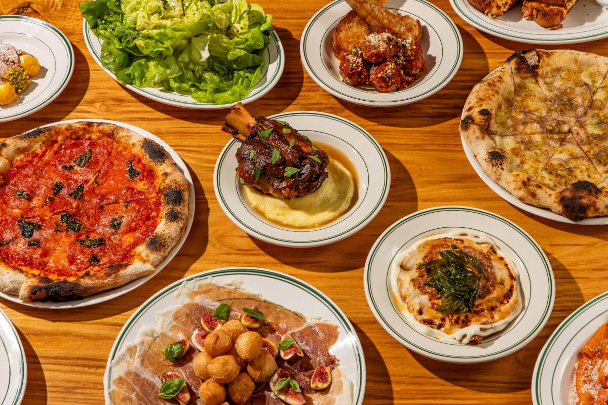A spread of dishes on a wood table at Hollywood's Jemma: pizza, salad, prosciutto with zeppole, osso buco and more.