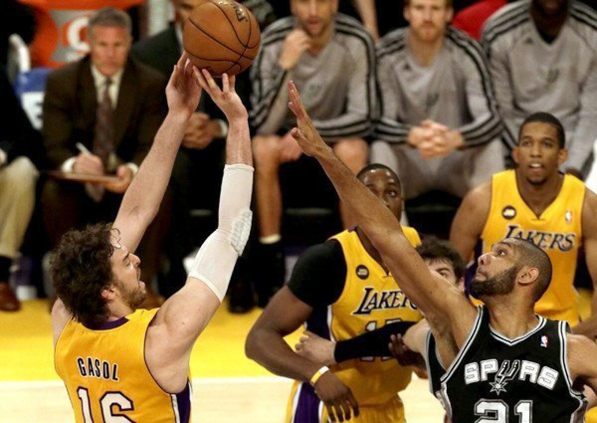 Lakers power forward Pau Gasol attempts a shot over the challenge of Spurs power forward Tim Duncan.