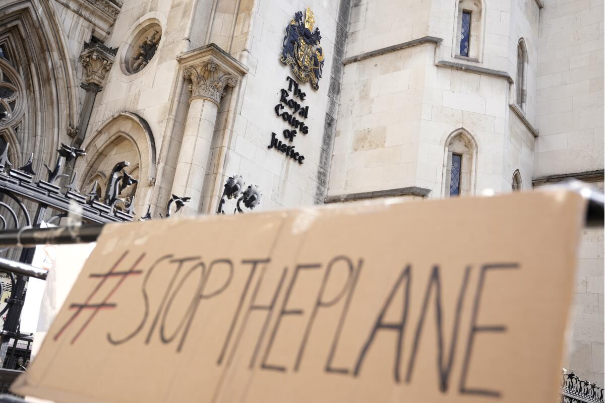 A sign that says "Stop the plane" left outside the High Court where the ruling on Rwanda deportation flights is taking place.