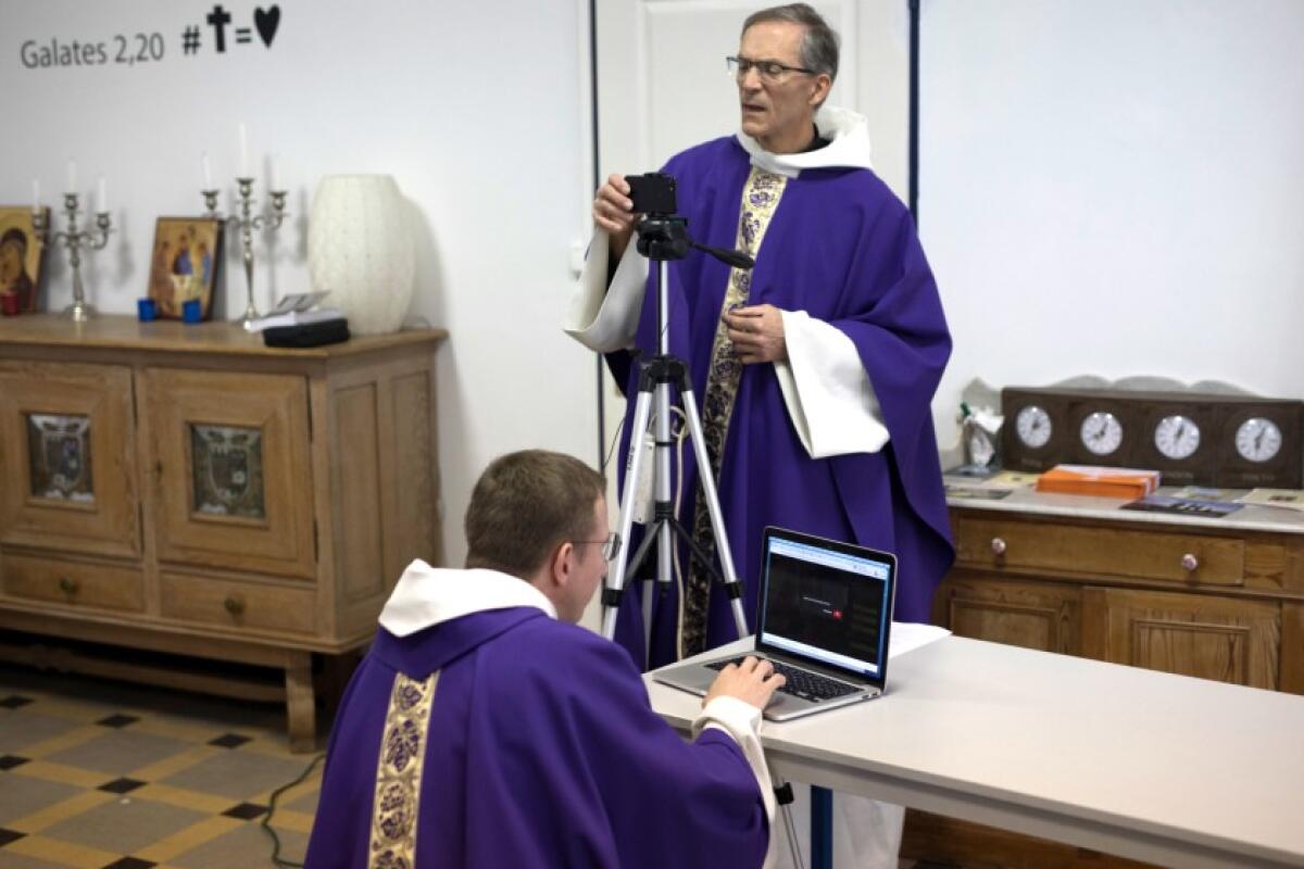 Priests Philippe Rochas, foreground, and Jean-Benoit de Beauchene pack up their equipment after livestreaming Mass from the St. Vincent de Paul church in Marseille, southern France, on March 22.