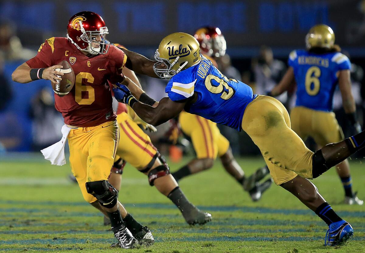 USC quarterback Cody Kessler breaks free from UCLA defensive lineman Owamagbe Odighizuwa to avoid a sack in the fourth quarter. The Bruins beat the Trojans, 38-20, on Saturday night at the Rose Bowl.