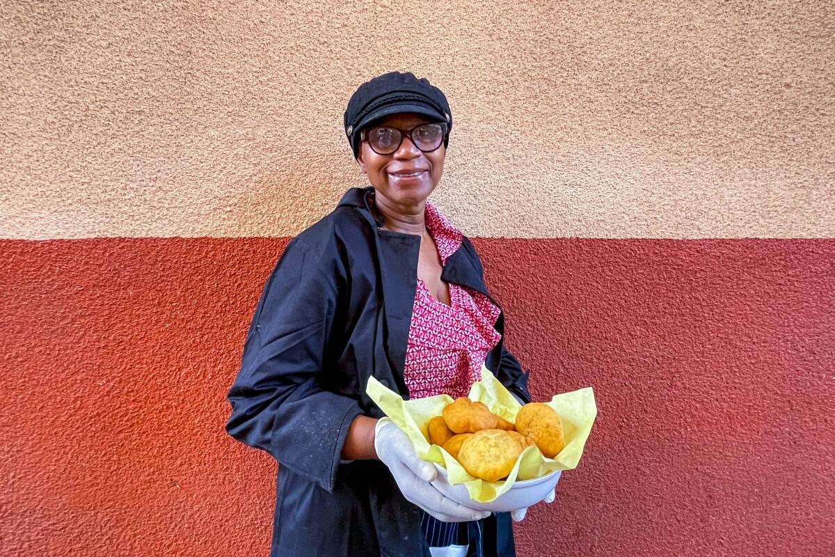 A woman holding a bowl of fresh festival bread and fried dumplings outside