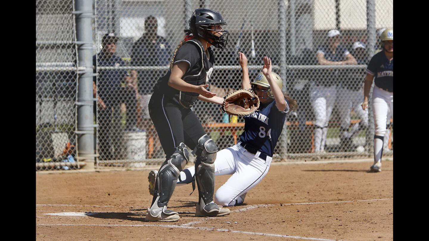 Huntington Beach High catcher Andie Belme waits for the throw at home plate as Chula Vista Mater Dei Catholic's Kirstin Kakacek slides in for a run during the second inning in a nonleague game at Huntington Beach High on Saturday, March 23, 2019.