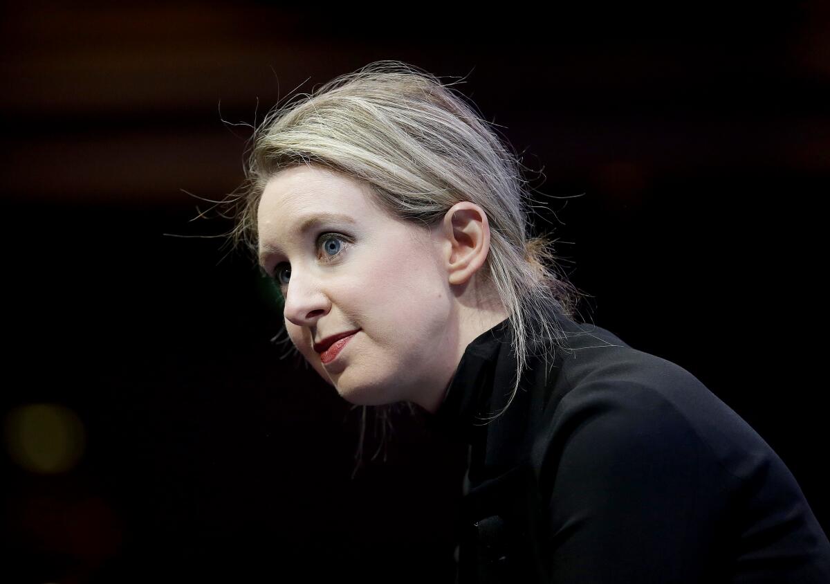 A close-up of Elizabeth Holmes in a black turtleneck against a black background.