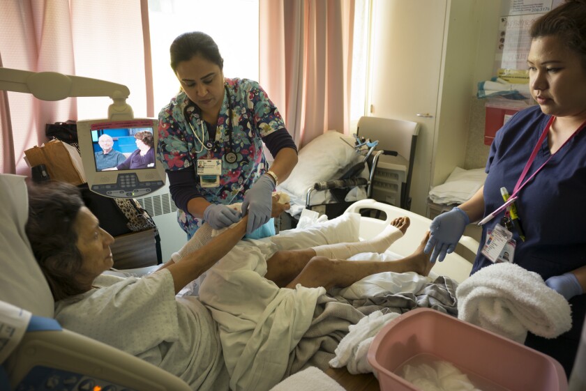 Geraldine Bordeaux, a patient at San Francisco General Hospital, is aided by nurses Brinder Bhuller, left, and Roxana Bartolo.