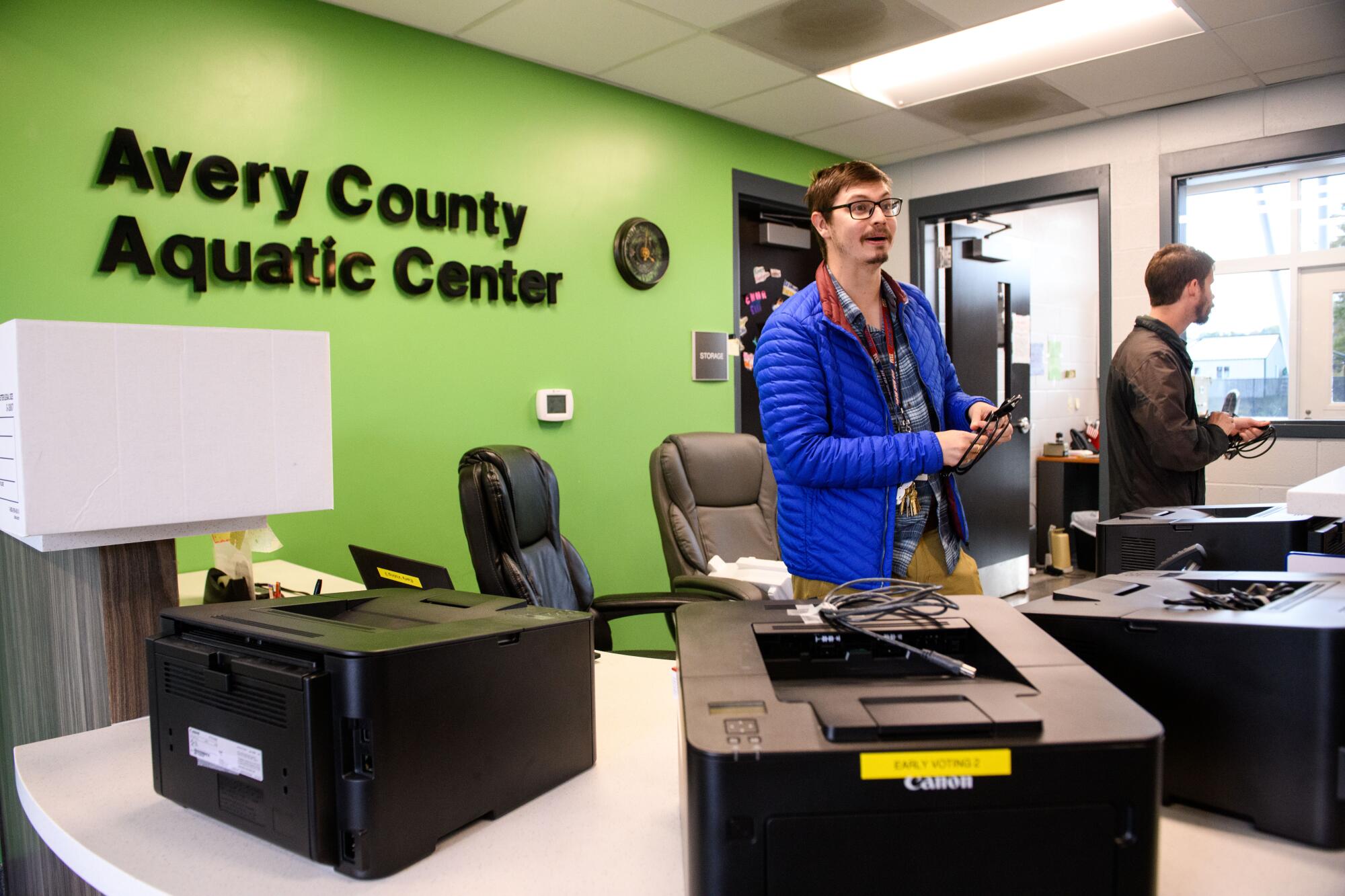 Elections official Joseph Trivette sets up equipment to handle ballots during early voting at an Aquatic Center.