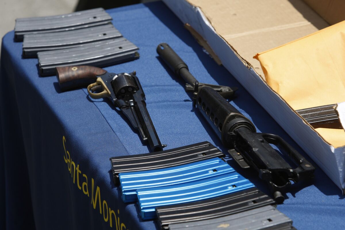 A pistol, part of an AR-15 type of gun and ammunition allegedly used during a mass shooting are displayed at Santa Monica Police Department headquarters.