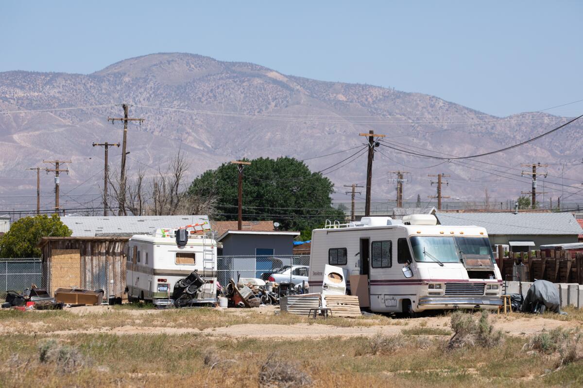 RVs parked on a dirt lot with mountains in the background