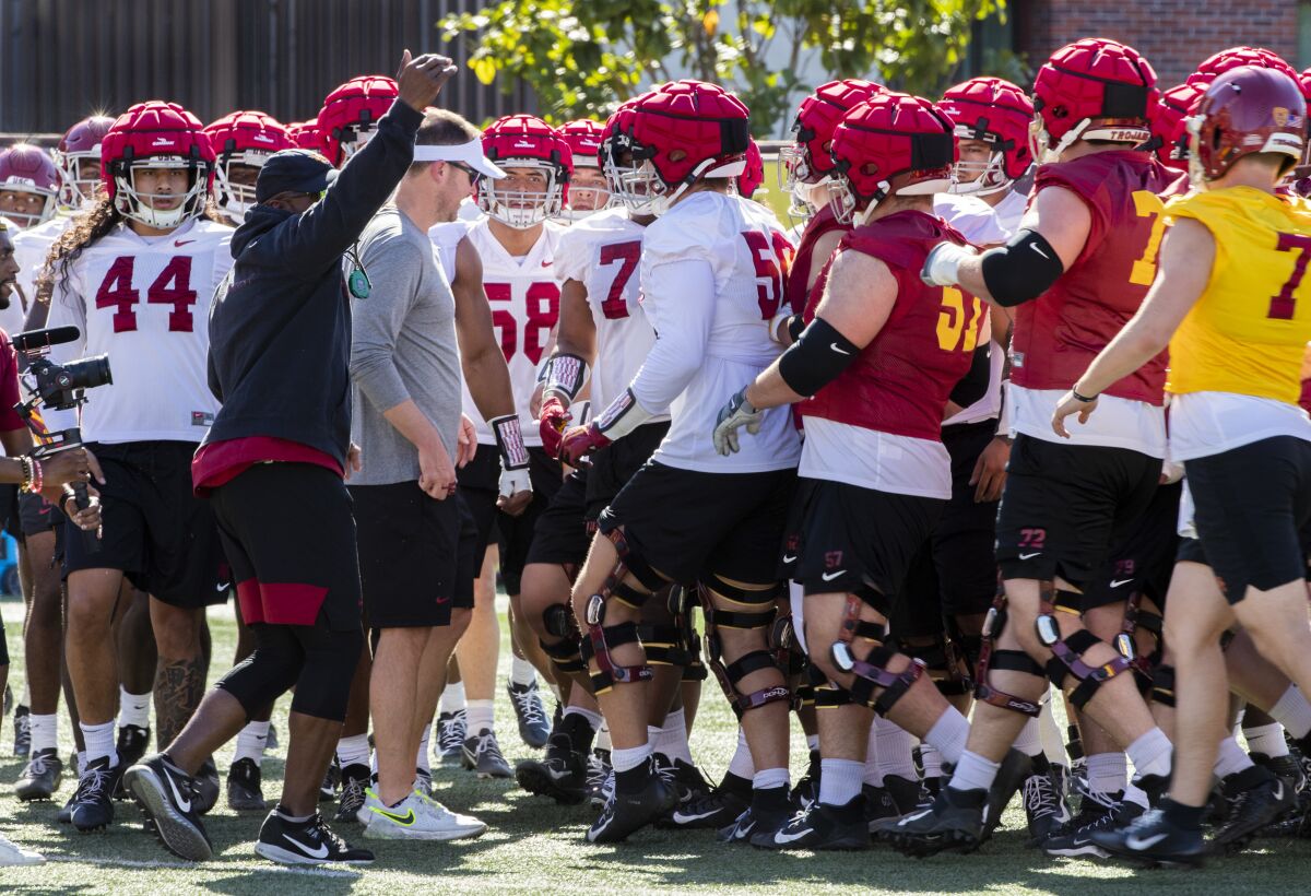 The USC football team huddles around coach Lincoln Riley during spring practice.