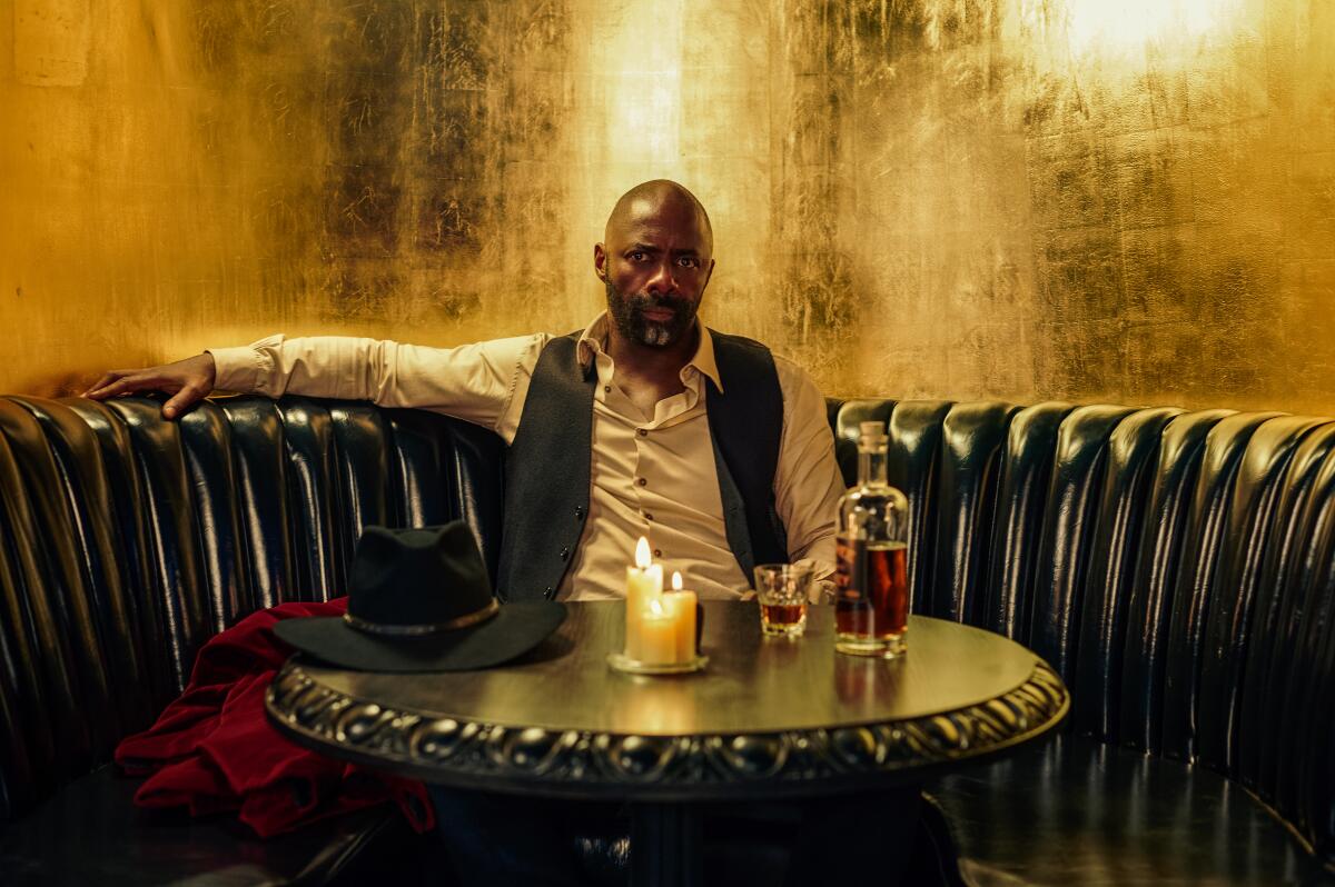 A man sits in a booth with candles lit on the table in front of him.