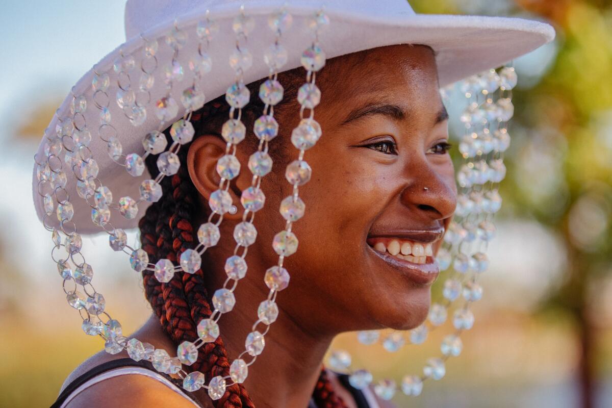 A young woman smiles while wearing a bejeweled cowboy hat.