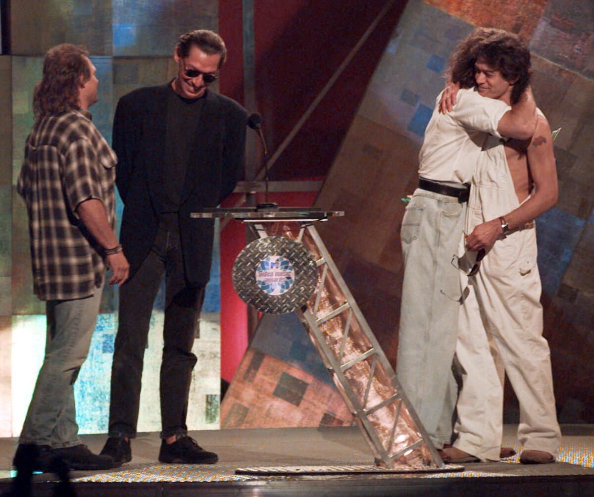 Former Van Halen band mates David Lee Roth and Eddie Van Halen, at right, embrace as they are reunite onstage at the MTV Video Music Awards in New York in 1996. Band mates Michael Anthony, left, and Alex Van Halen are also present