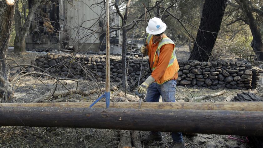 In this Oct. 18, 2017, file photo, a Pacific Gas & Electric Co. worker replaces a power pole destroyed by wildfire in Glen Ellen, Calif.