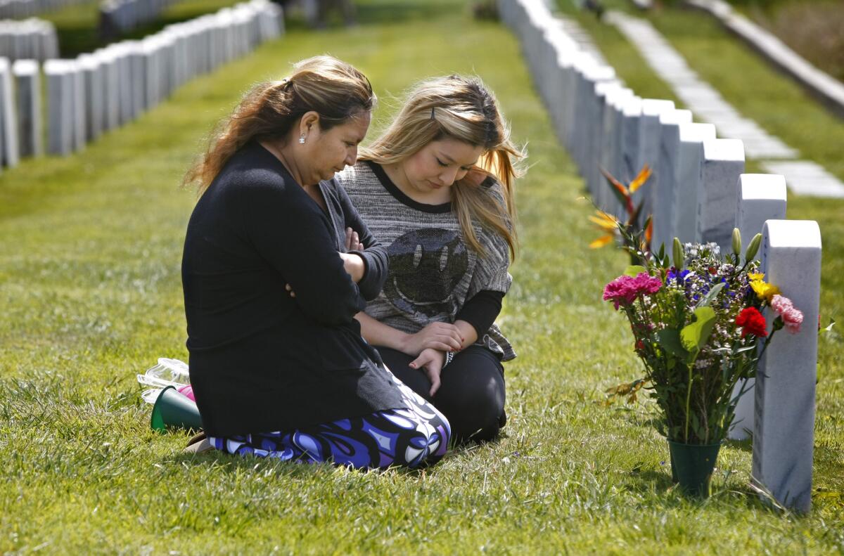 Rosa Peralta, left, with her daughter, Karen, kneels before the grave of her son, Marine Sgt. Rafael Peralta, at Fort Rosecrans National Cemetery in San Diego. Rafael Peralta was killed in Iraq in 2004.