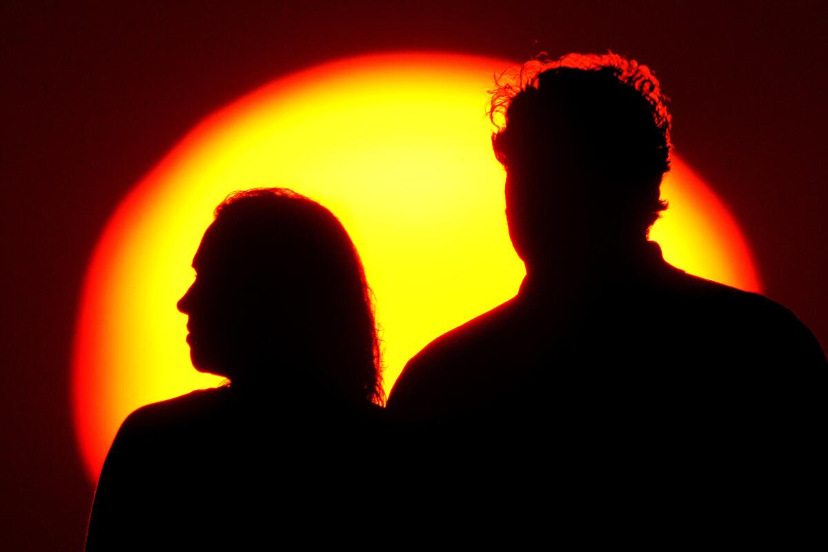 A woman and man with the sun setting behind them