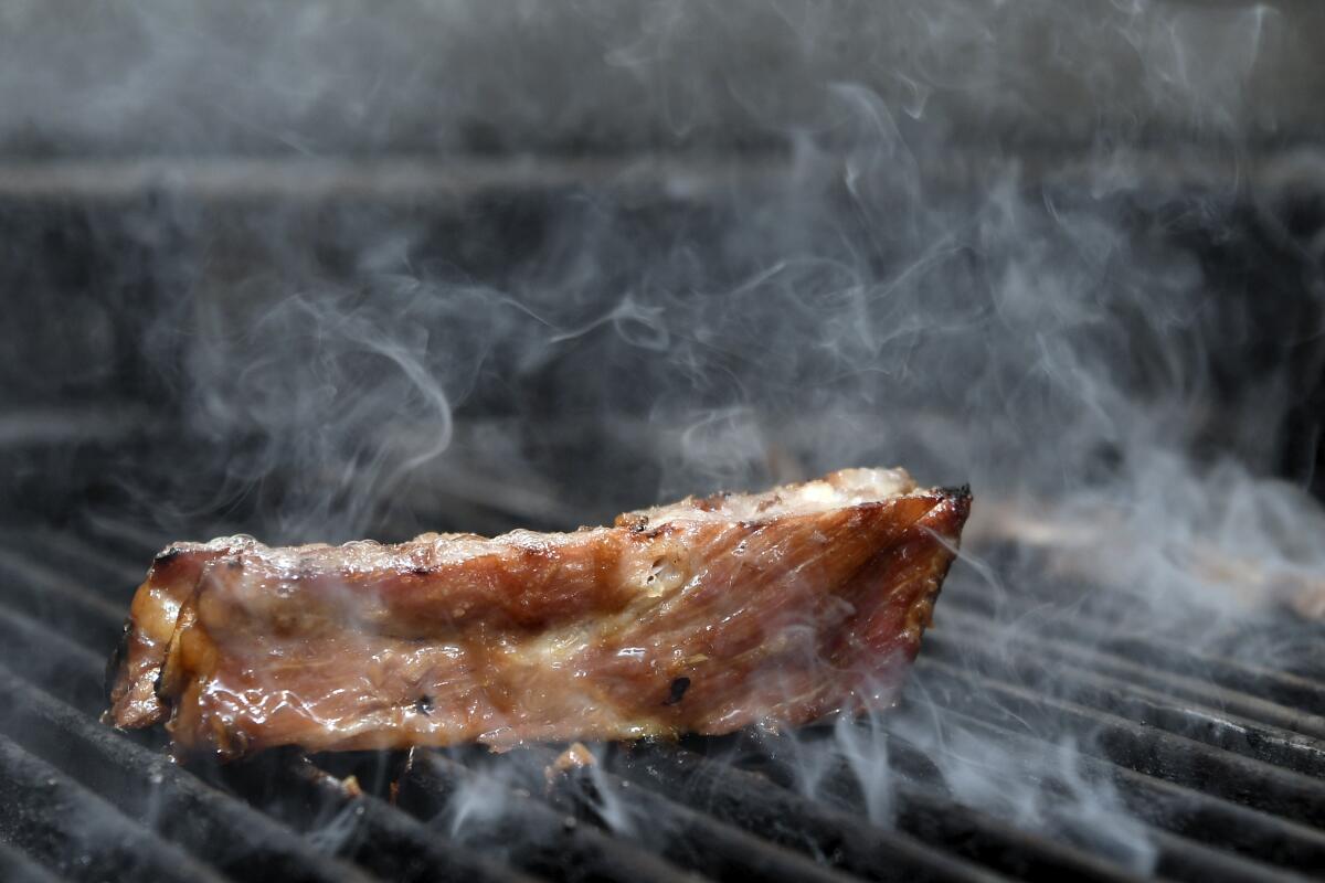 A piece of meat cooking on a grill.