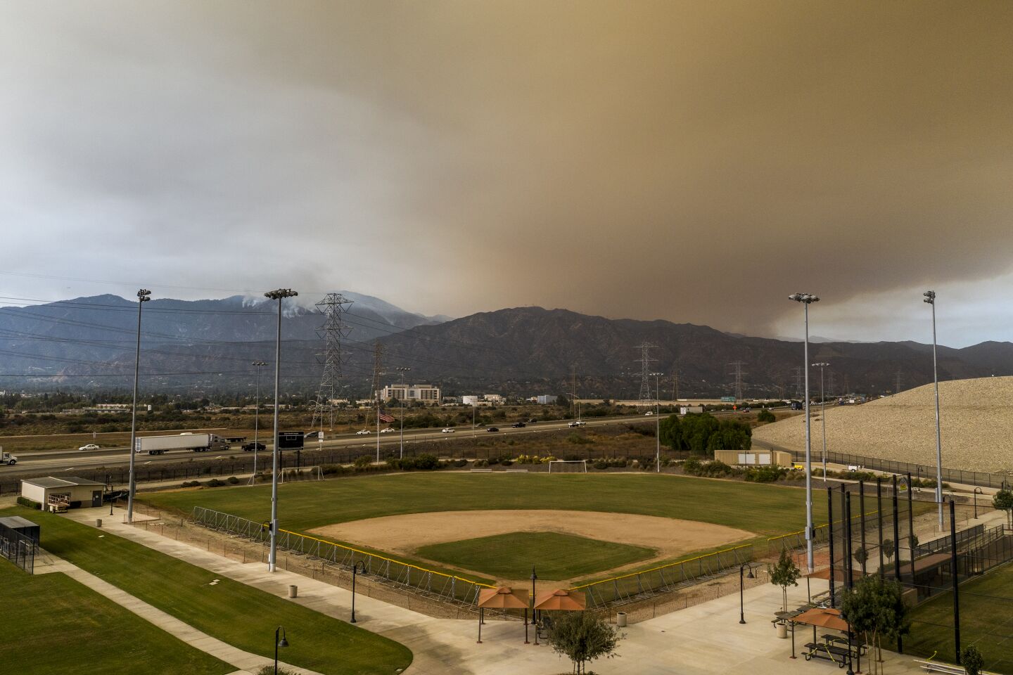 Haze from the Bobcat fire looms over a baseball diamond