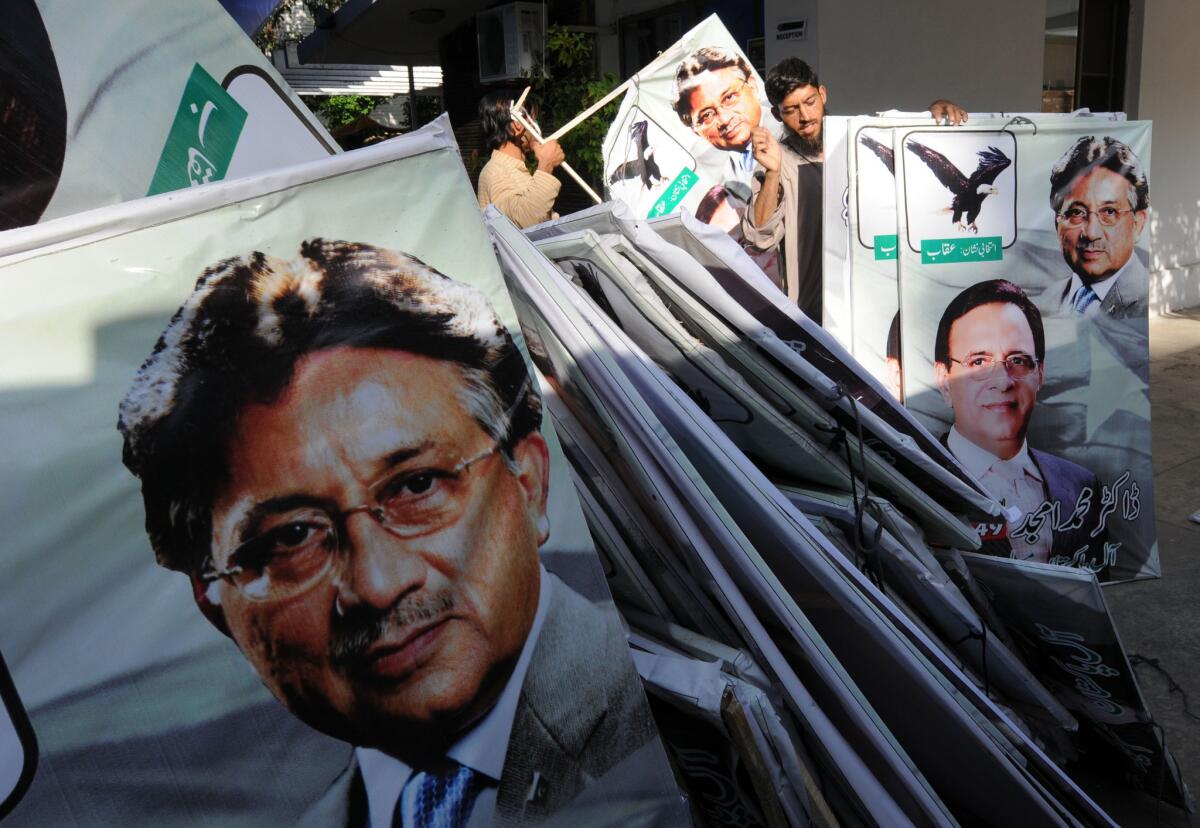 Supporters of former Pakistani President Pervez Musharraf place election banners featuring his image, foreground, at their party office in Islamabad on Tuesday.