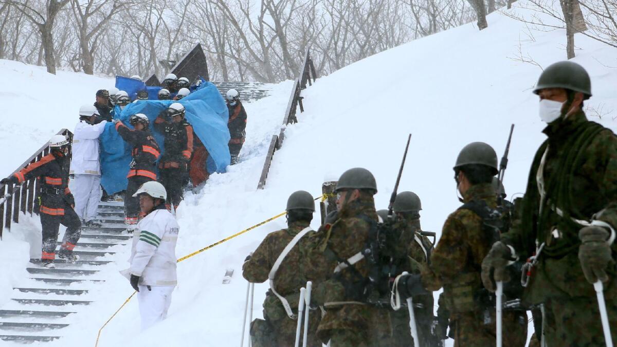 Firefighters carry a survivor they rescued from the site of an avalanche in Nasu town, Tochigi prefecture on March 27 while Self Defense Force personnel look on. (Jiji Press / AFP/Getty Images)