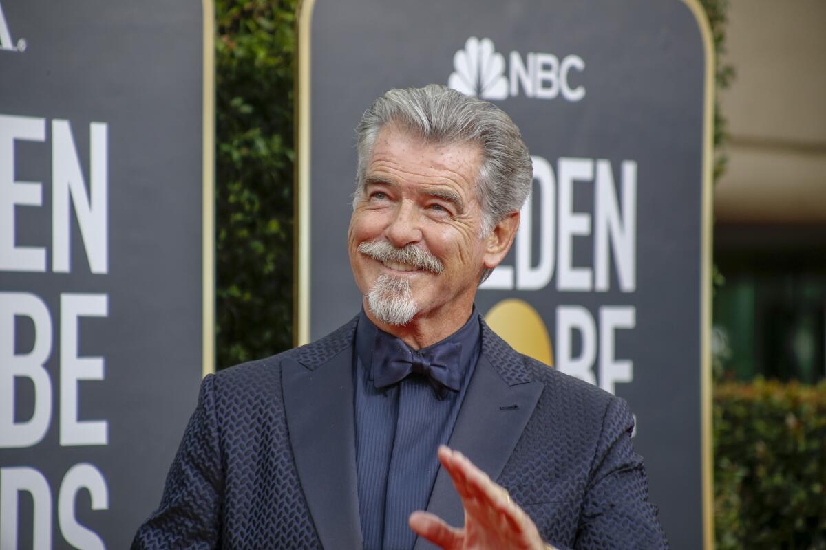 Pierce Brosnan wears a blue and black tuxedo as he poses for photos on the Golden Globes red carpet. 