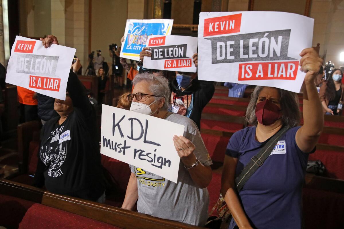 Protesters hold signs reading "Kevin de León is a liar" and "KDL must resign" during Tuesday's L.A. City Council meeting. 